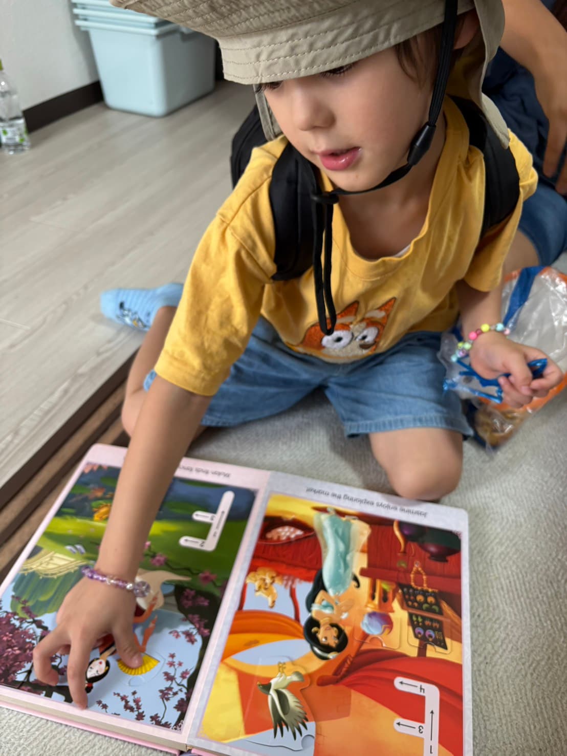 A child exploring an illustrated picture book on the floor